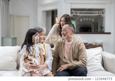 Family is spending joyful moments in comfortable living room, with three generations present. grandparents are smiling at their granddaughter, while the mother enjoys the warm atmosphere. Family is spending joyful moments in comfortable living room, with three generations present. grandparents are smiling at their granddaughter, while the mother enjoys the warm atmosphere. 123846773