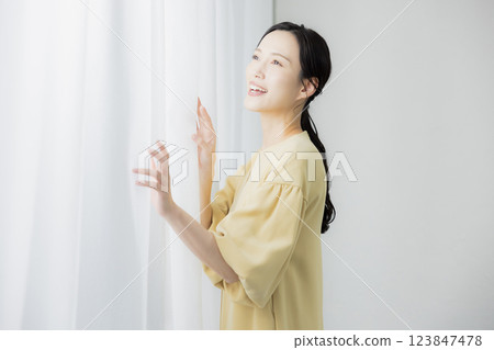 Woman opening curtain Woman opening curtain 123847478