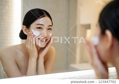 A woman doing skin care in front of a mirror Generative AI 123847702