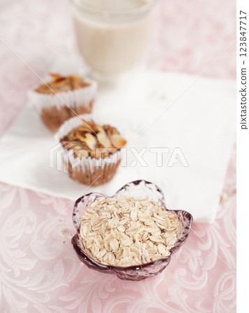 Oatmeal in small glass bowl with oatmeal muffins in background. healthy food. 123847717