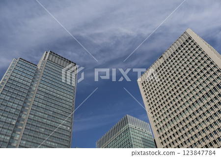 Cityscape of an urban office district with skyscrapers and white clouds looking up at the blue sky Cityscape of an urban office district with skyscrapers and white clouds looking up at the blue sky 123847784