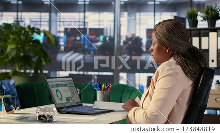 African american confident CEO working in corporate office with data analysis, focusing on career development to increase funding and revenue. Productive goal oriented director for growth. Camera A. African american confident CEO working in corporate office with data analysis, focusing on career development to increase funding and revenue. Productive goal oriented director for growth. Camera A. 123848819