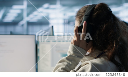 Engineer typing on computer in server hub, checking recovery plan, monitoring data center energy consumption, listening music. Technician wearing headphones inspecting rackmounts, camera A close up Engineer typing on computer in server hub, checking recovery plan, monitoring data center energy consumption, listening music. Technician wearing headphones inspecting rackmounts, camera A close up 123848848