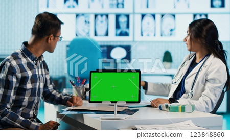 Medical expert and male patient meeting in office next to isolated copy space, reading diagnosis from test results. Modern gadget with mockup running during check up appointment. Camera A. Medical expert and male patient meeting in office next to isolated copy space, reading diagnosis from test results. Modern gadget with mockup running during check up appointment. Camera A. 123848860