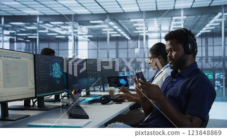 Admin in server room using mobile phone, relaxing after ensuring minimal downtime. Data center IT expert texting on smartphone, taking break from monitoring performance, camera A Admin in server room using mobile phone, relaxing after ensuring minimal downtime. Data center IT expert texting on smartphone, taking break from monitoring performance, camera A 123848869