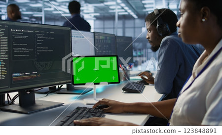Data center programmer using mockup tablet, maintaining company network infrastructure, close up. Server hub worker ensuring optimal system performance with isolated screen device, camera A 123848891