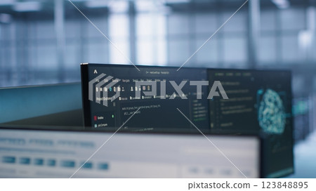 Close up of code on computer screens in high tech facility responsible with intense data computations demanding scalable, error free network to support AI machine learning, handheld camera shot 123848895