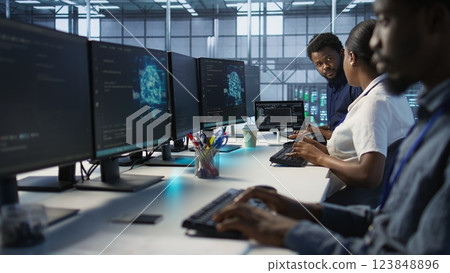 IT specialists in data center doing brainstorming, maintaining company network infrastructure. Team of server hub computer scientists chatting, ensuring optimal system performance, camera A IT specialists in data center doing brainstorming, maintaining company network infrastructure. Team of server hub computer scientists chatting, ensuring optimal system performance, camera A 123848896