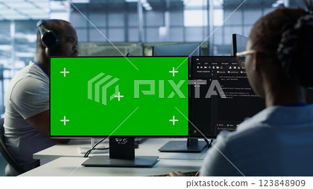 IT specialist in server farm using green screen PC ensuring valuable data remains shielded from threats. Woman safeguarding hardware against unauthorized access using mockup computer, camera A 123848909