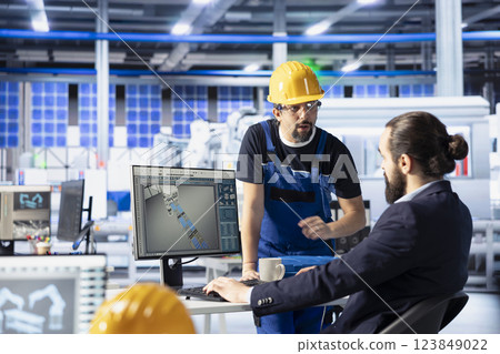 Solar panels plant manager teaching intern how to optimize efficiency based on analysis data. Photovoltaics factory team leader guiding new employee working on innovative solar cells design prototype 123849022
