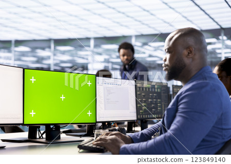 Server room facility admin ensuring data remains shielded from potential threats using mockup PC. Man safeguarding data center workplace against hackers with isolated screen computer Server room facility admin ensuring data remains shielded from potential threats using mockup PC. Man safeguarding data center workplace against hackers with isolated screen computer 123849140