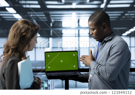 Engineers in data center using isolated screen notebook, observing analytics, reviewing equipment health. Workers using mockup laptop, adjusting system parameters, doing maintenance tasks 123849152