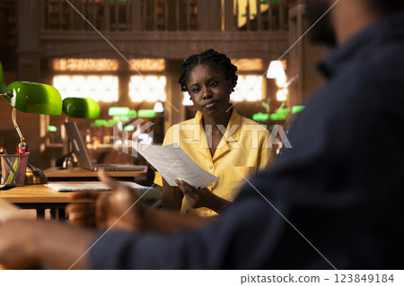 Black dedicated scholars work on their thesis project in the quiet wooden library, sharing ideas and comparing class notes for research completion. Achieving academic success together. Black dedicated scholars work on their thesis project in the quiet wooden library, sharing ideas and comparing class notes for research completion. Achieving academic success together. 123849184