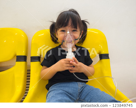 sick toddler baby girl using steam inhaler with nebulizer mask inhalation in hospital 123849745