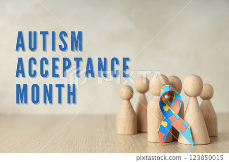 Autism Day, wooden figurines of men and ribbon with colorful puzzle on a light wooden background, with text Autism Day, wooden figurines of men and ribbon with colorful puzzle on a light wooden background, with text 123850015
