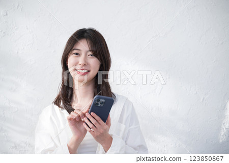A woman using a smartphone on a sunny white background A woman using a smartphone on a sunny white background 123850867