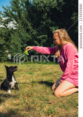 Young woman playing with her dog and shuttlecocks concept. Summer outdoor activities. Staycation leisure time. Petrenthood pet love 123850980