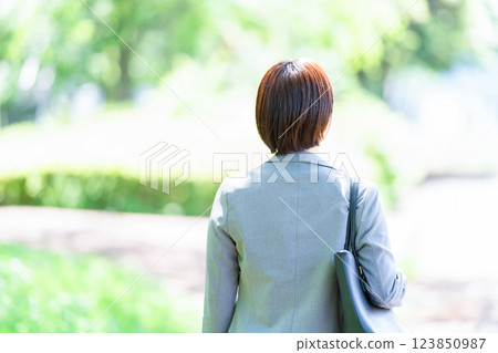 A woman in a suit walking in a park, a business woman, a businessman in a fresh green 123850987