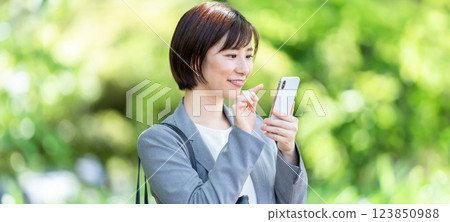 A woman in a suit who uses a smartphone, a business woman 123850988