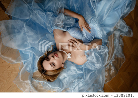 A woman in a blue gown is laying on the floor 123851013