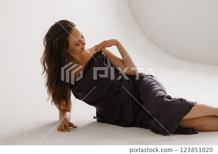 Elegant Woman in a Dark Slip Dress Posing on a White Background 123851020