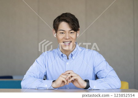 A man in his 30s wearing earphones talking to the camera A man in his 30s wearing earphones talking to the camera 123852554
