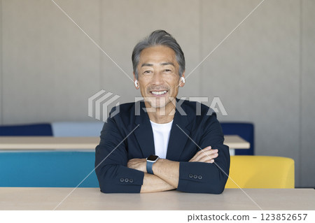 A smiling man in his 60s wearing earphones talking while looking at the camera A smiling man in his 60s wearing earphones talking while looking at the camera 123852657