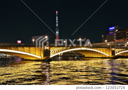 The golden lit-up Kuramae Bridge over the Sumida River and the red Skytree at night 123852728