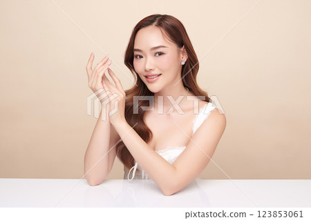 A beautiful young Asian woman with clean, fresh skin against a beige background. She represents beauty, skincare, and spa treatments. A beautiful young Asian woman with clean, fresh skin against a beige background. She represents beauty, skincare, and spa treatments. 123853061