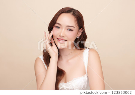 A beautiful young Asian woman with clean, fresh skin against a beige background. She represents beauty, skincare, and spa treatments. A beautiful young Asian woman with clean, fresh skin against a beige background. She represents beauty, skincare, and spa treatments. 123853062