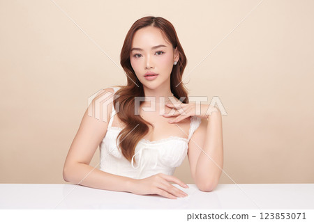 A beautiful young Asian woman with clean, fresh skin against a beige background. She represents beauty, skincare, and spa treatments. 123853071