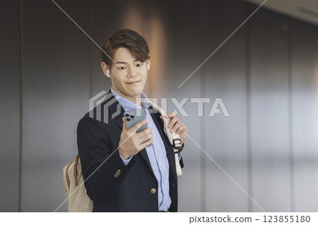 一位 30 多歲的商人戴著耳機看著智慧型手機螢幕 123855180