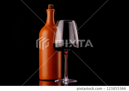 Elegant presentation of red wine in a glass and a bottle against a dark background 123855366