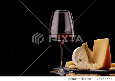 A refined selection of aged cheeses presented on a board, accompanied by a glasses of wine 123855367