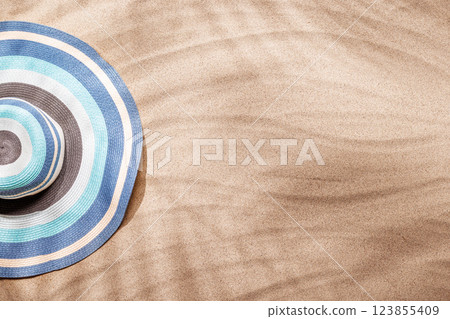 A tropical summer background featuring soft beach sand with delicate palm leaf shadows and sunhat A tropical summer background featuring soft beach sand with delicate palm leaf shadows and sunhat 123855409