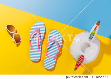 A vibrant summer vacation scene with flip flops, shades, and a floating flamingo 123855435