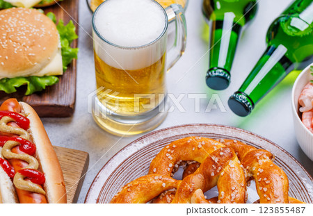A vibrant photo showcasing a glass of beer surrounded by various snacks and fast food 123855487