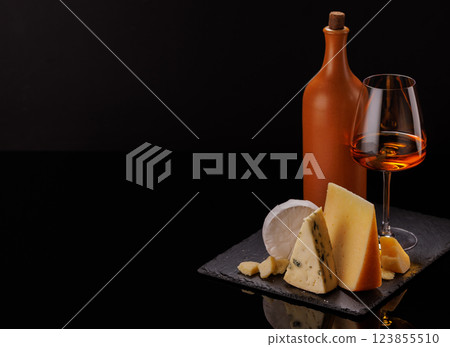 A refined selection of aged cheeses presented on a board, accompanied by a glasses of wine 123855510