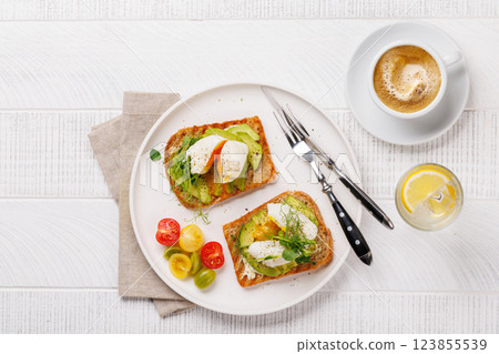 Delicious avocado toasts topped with perfectly cooked poached eggs Delicious avocado toasts topped with perfectly cooked poached eggs 123855539