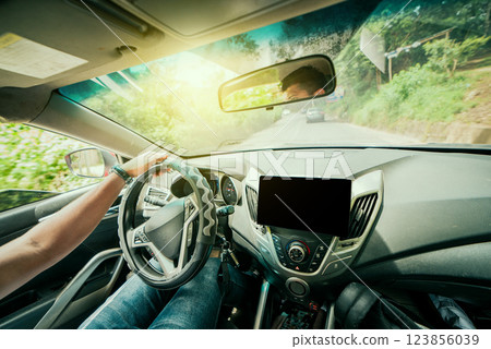 View of man driving a car on the road. Male hands behind the wheel of the car View of man driving a car on the road. Male hands behind the wheel of the car 123856039