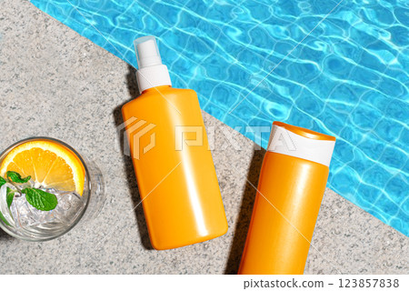 Sunscreen products and cocktail drink near pool water 123857838