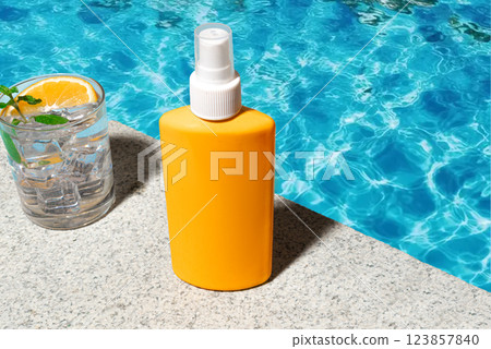 Sunscreen bottle near blue pool water Sunscreen bottle near blue pool water 123857840
