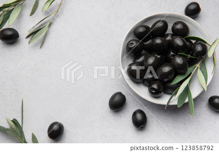 Black olives in a bowl with olive branches on gray background, concept of mediterranean diet 123858792