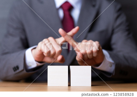 一位中年男性商人用兩塊白色木塊做十字標誌 一位中年男性商人用兩塊白色木塊做十字標誌 123858928