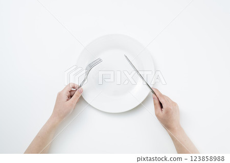 Woman holding a simple white plate, fork and knife 123858988