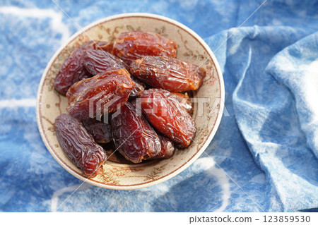 Dried dates fruit in bowl on blue cotton. Top view. 123859530