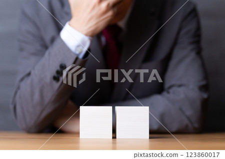 一位身穿西裝、手裡拿著兩塊白色木塊的中年男性商人 123860017