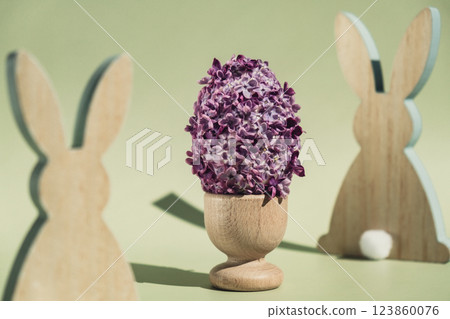 Creative Easter egg shape made of lilac spring petals flowers. Eco-friendly wooden bunnies decoration. Minimal holiday concept still life. Copy space greeting card 123860076