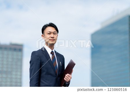 Businessman with binder outdoors 123860516