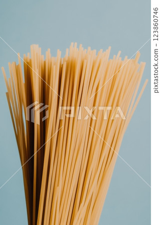 Bunch of uncooked spaghetti pasta on blue background 123860746
